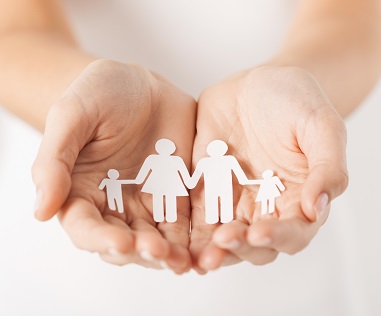 Picture of outstretched hands with a paper cutout of a family in them.